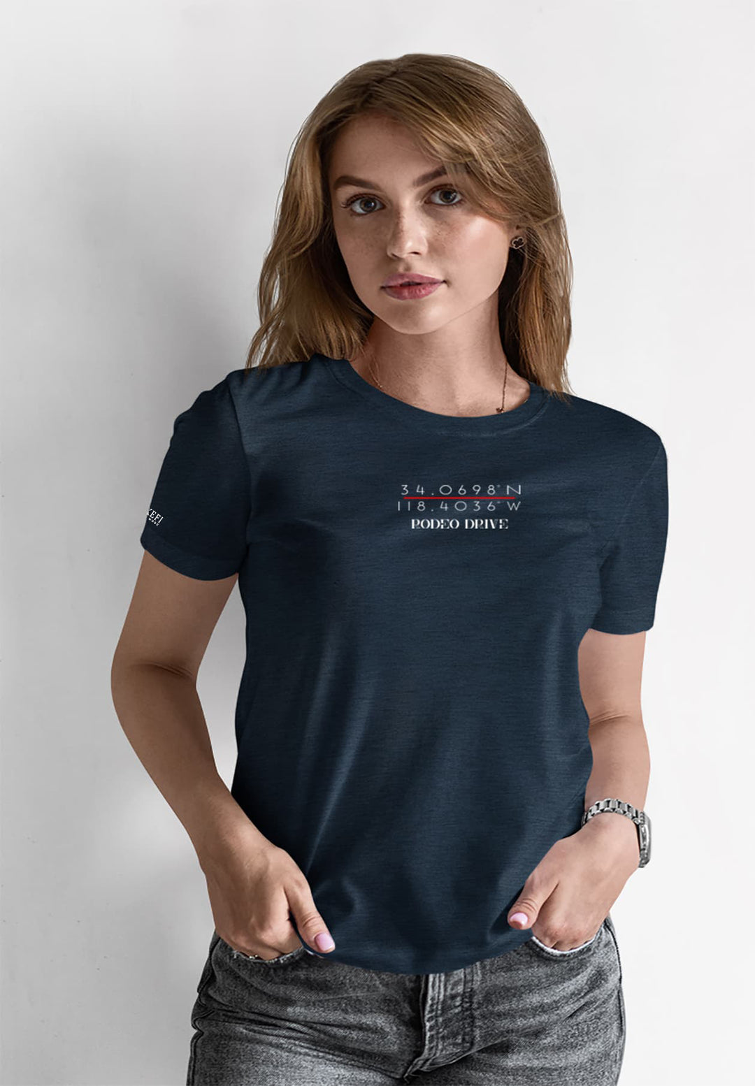 In a casual elegance, a woman stands gracefully in a blue T-shirt paired with gray jeans, embodying a relaxed yet stylish charm.