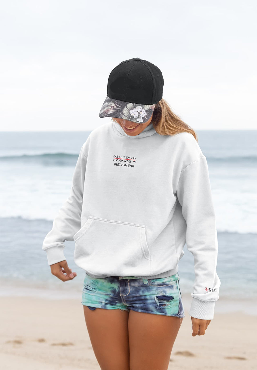 The woman's white hoodie becomes a symbol of coastal leisure as she enjoys a walk on the beach, fashioning a memory of relaxation and seaside bliss.