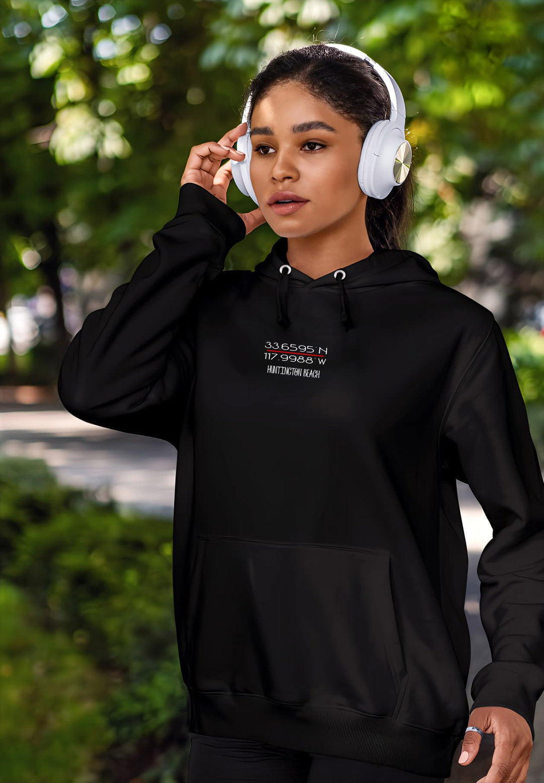 Embracing her musical journey, the woman walks with headphones and a black hoodie, creating a moment of effortless urban cool and personalized style.