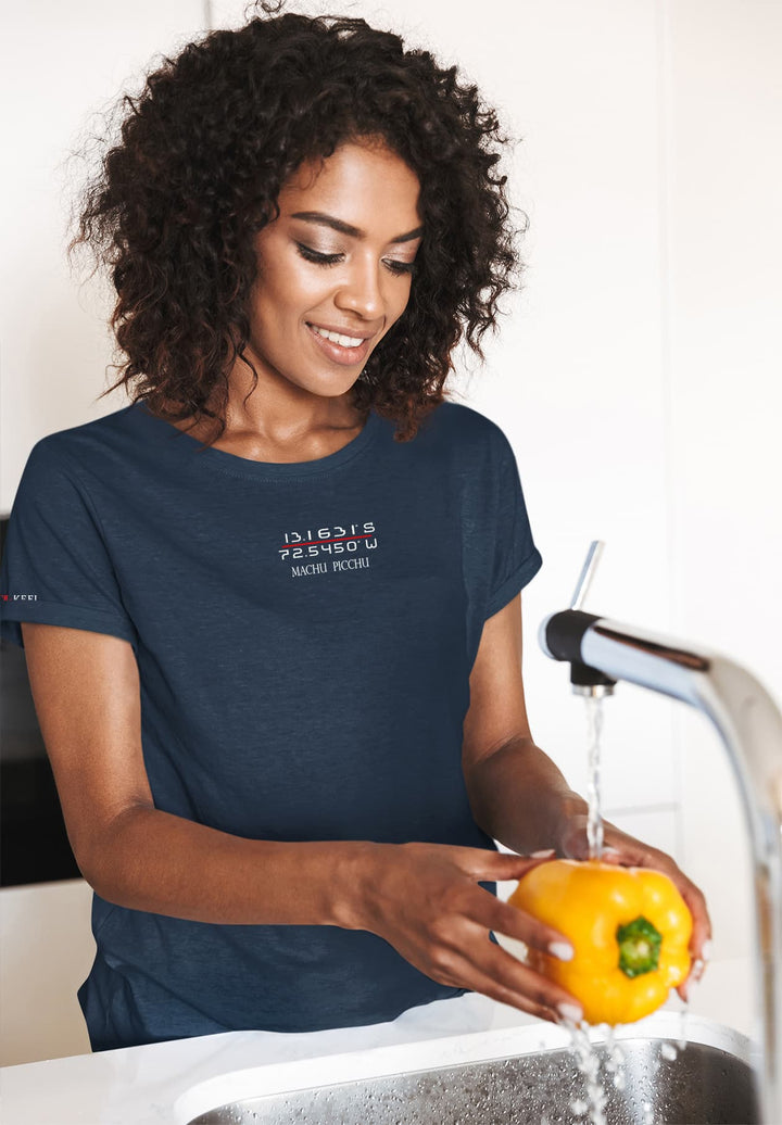 A woman embraces the simple joy of preparing a meal, her blue T-shirt a canvas for the vibrant dance of water and fresh produce.