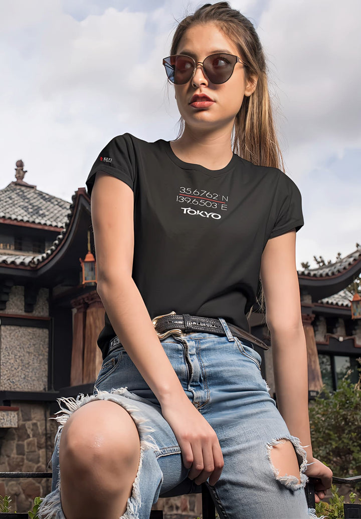 A woman stands by an oriental house, her black tee blending with the mystique, a moment painted with timeless beauty.
