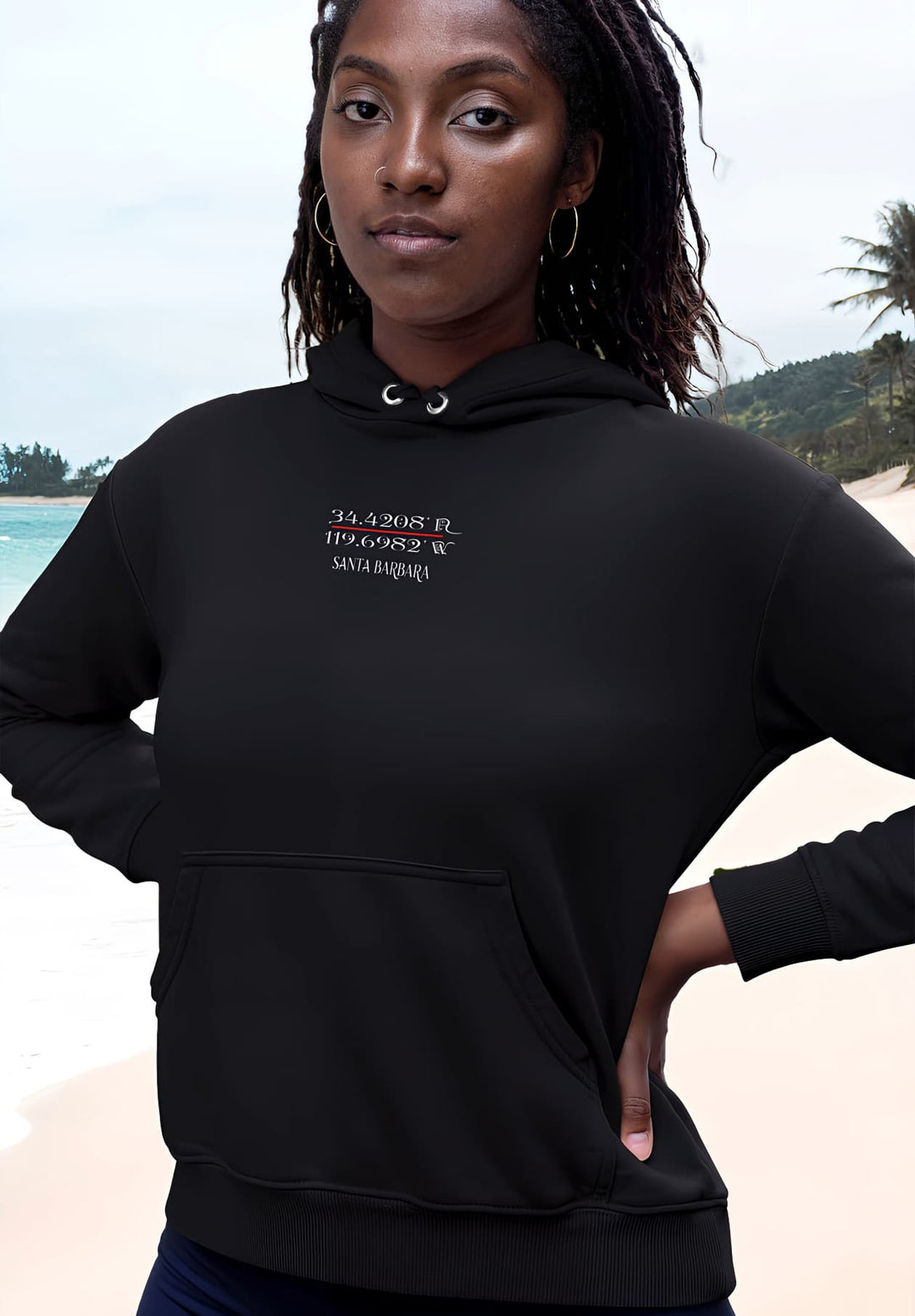 A woman graces the beach, enveloped in the comforting allure of a black hoodie. 