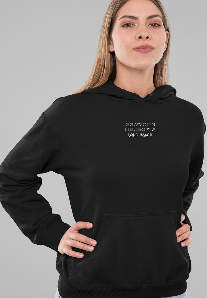 The woman wears a black hoodie with Long Beach coordinates, combining comfort and local pride.
