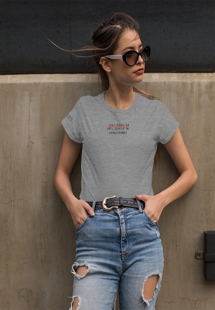 Wearing a gray t-shirt and fashionable ripped jeans, a woman captures an effortless blend of casual charm and trendy allure.