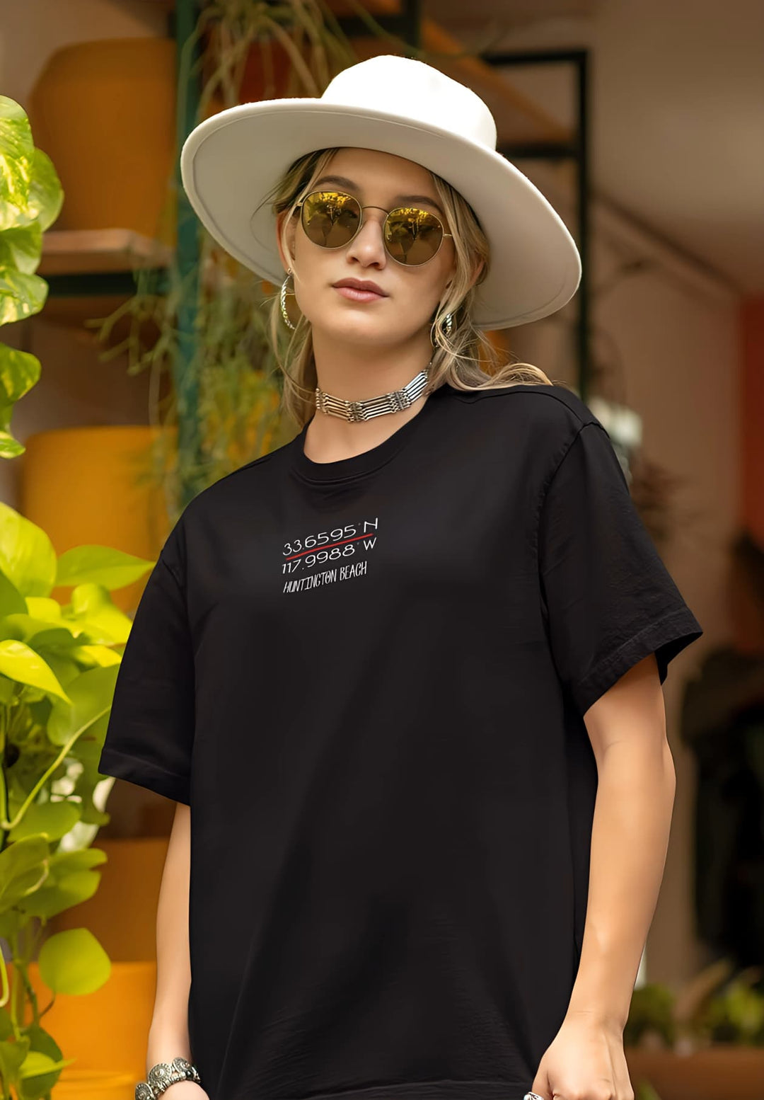 A stylish woman exudes confidence in her black T-shirt and hat, creating an effortlessly chic and captivating look.