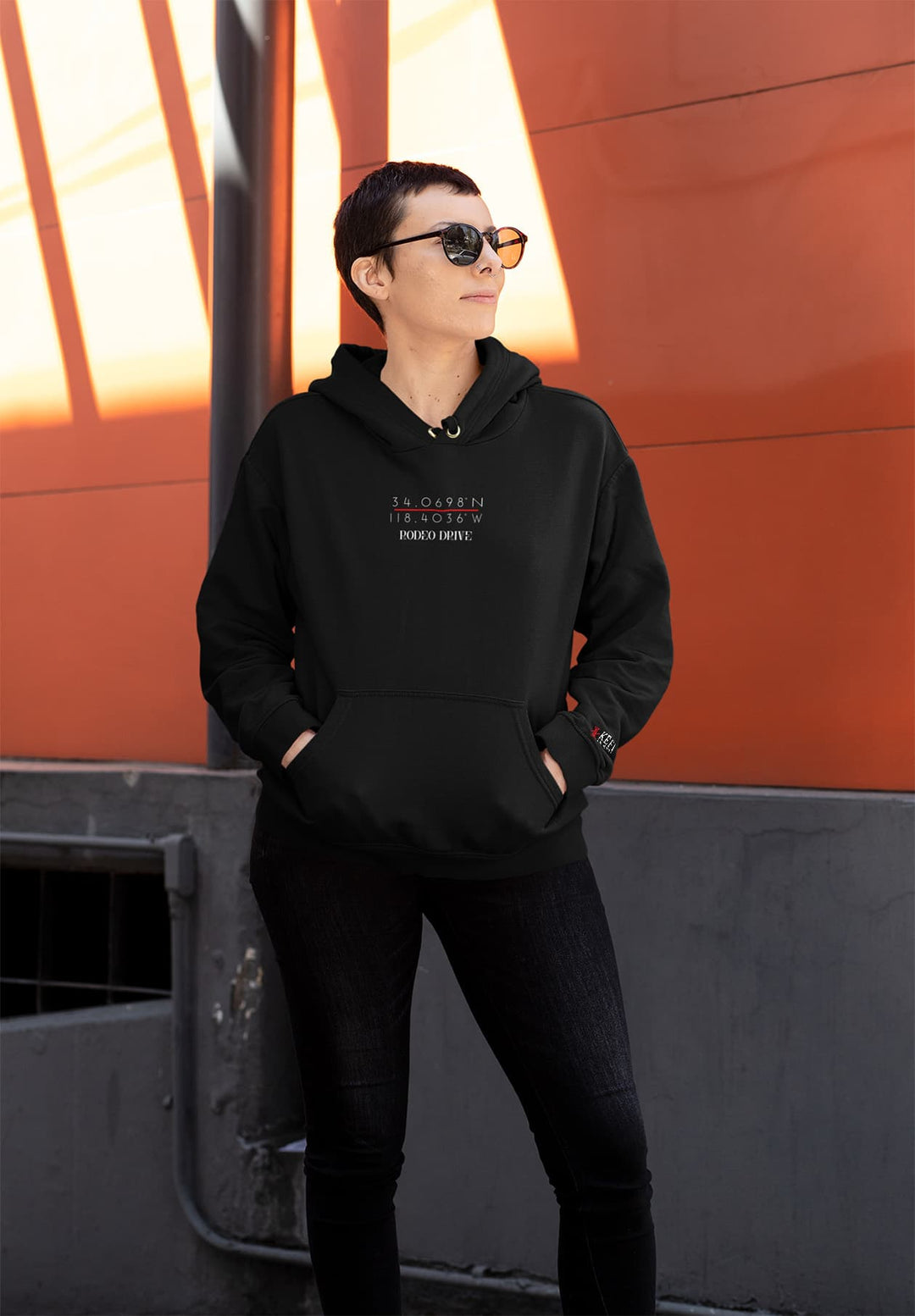 A woman wears a trendy black hoodie and sunglasses that reflect urban chic.