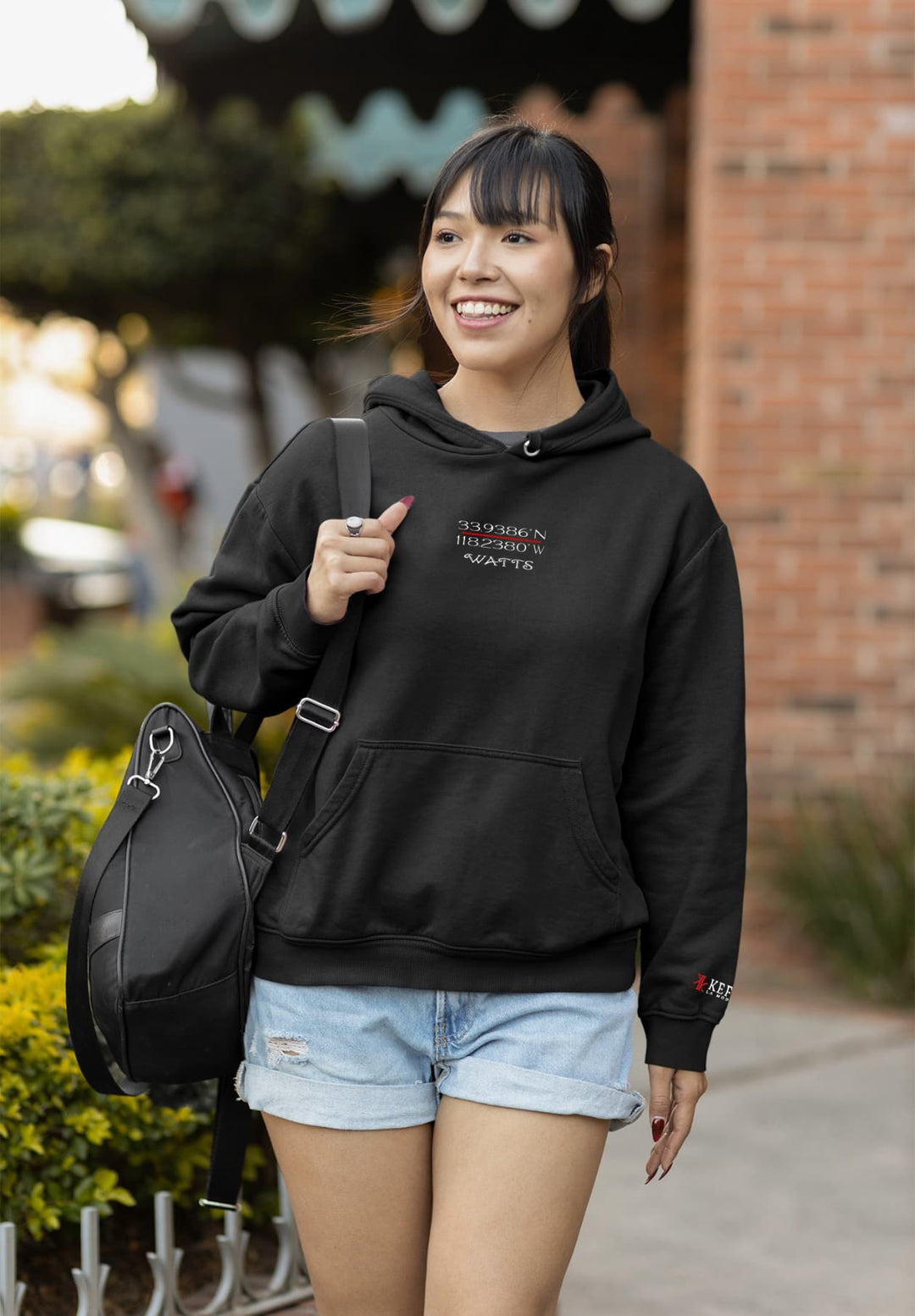 A woman walking down the street with a purse wearing a black sweatshirt.