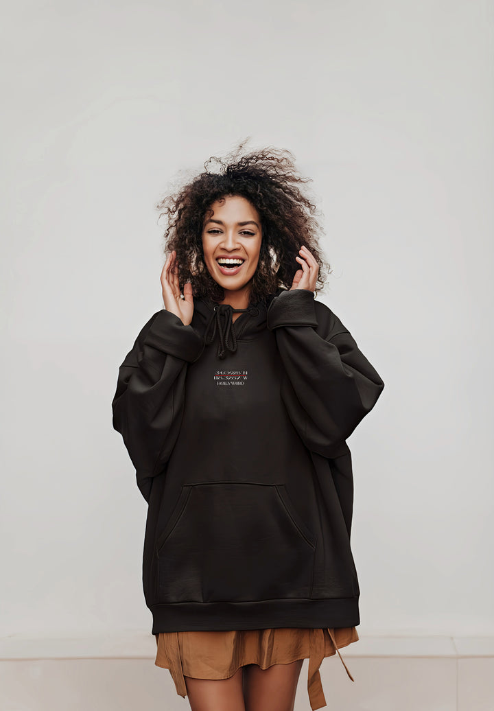 The woman's curly hair adds a touch of playfulness to the ensemble, as she dons an oversized black hoodie, creating a memory of contemporary comfort and style.