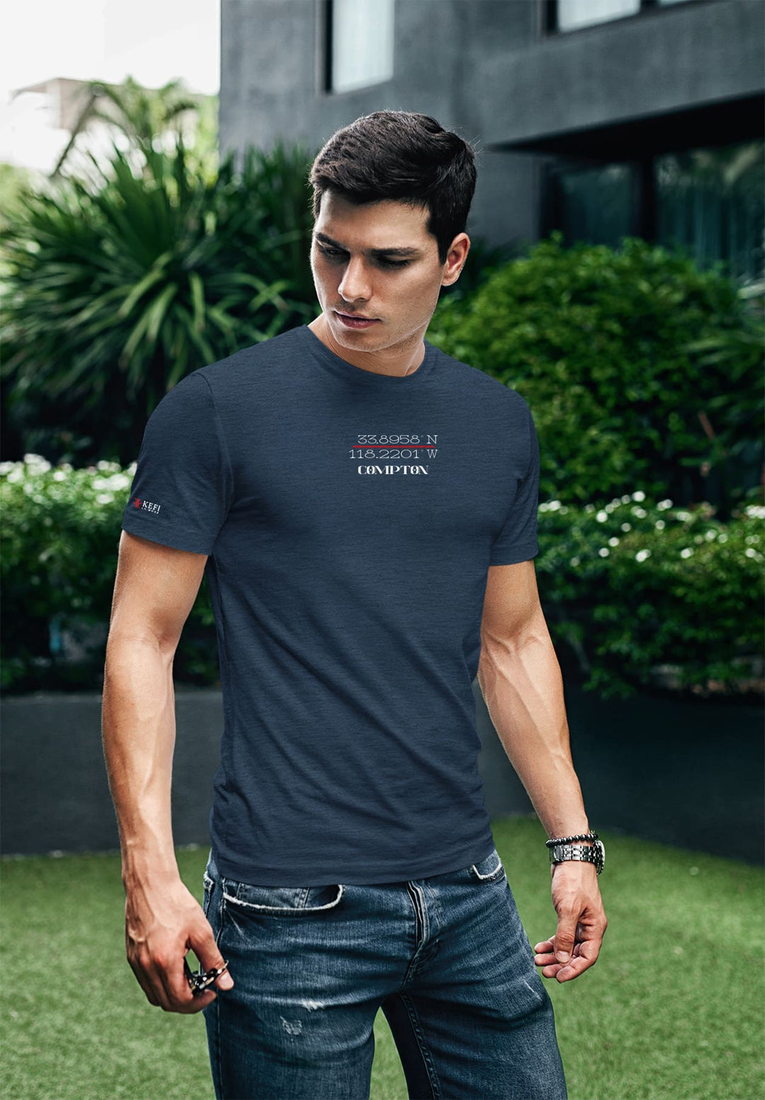 Amidst the courtyard's embrace, a young man stands, his dark blue tee echoing the calm whispers of tranquil moments.