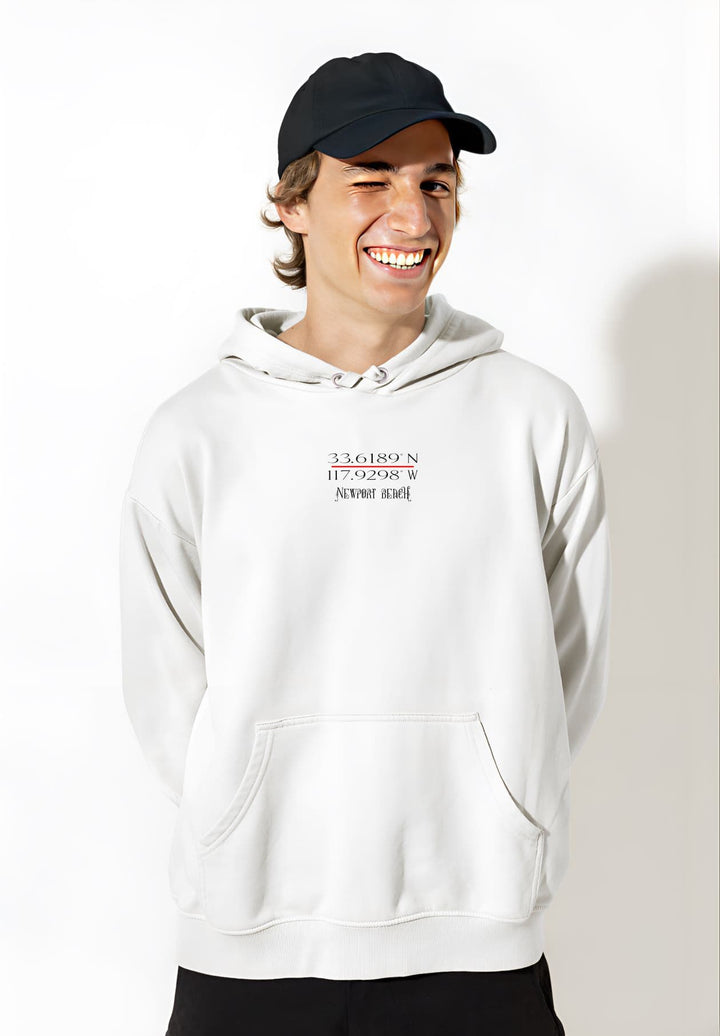 Sporting a white Newport Beach hoodie and a black cap, the young man exudes urban chic and youthful flair.