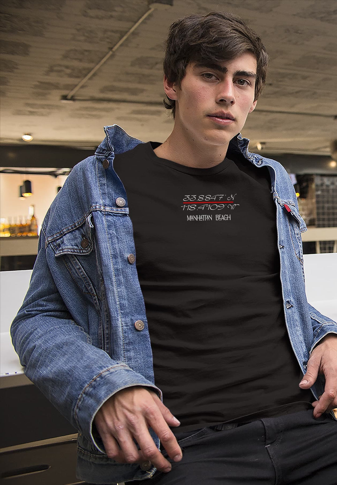 The young man wears a black T-shirt and jean jacket, his attire a reflection of his individuality and timeless style.