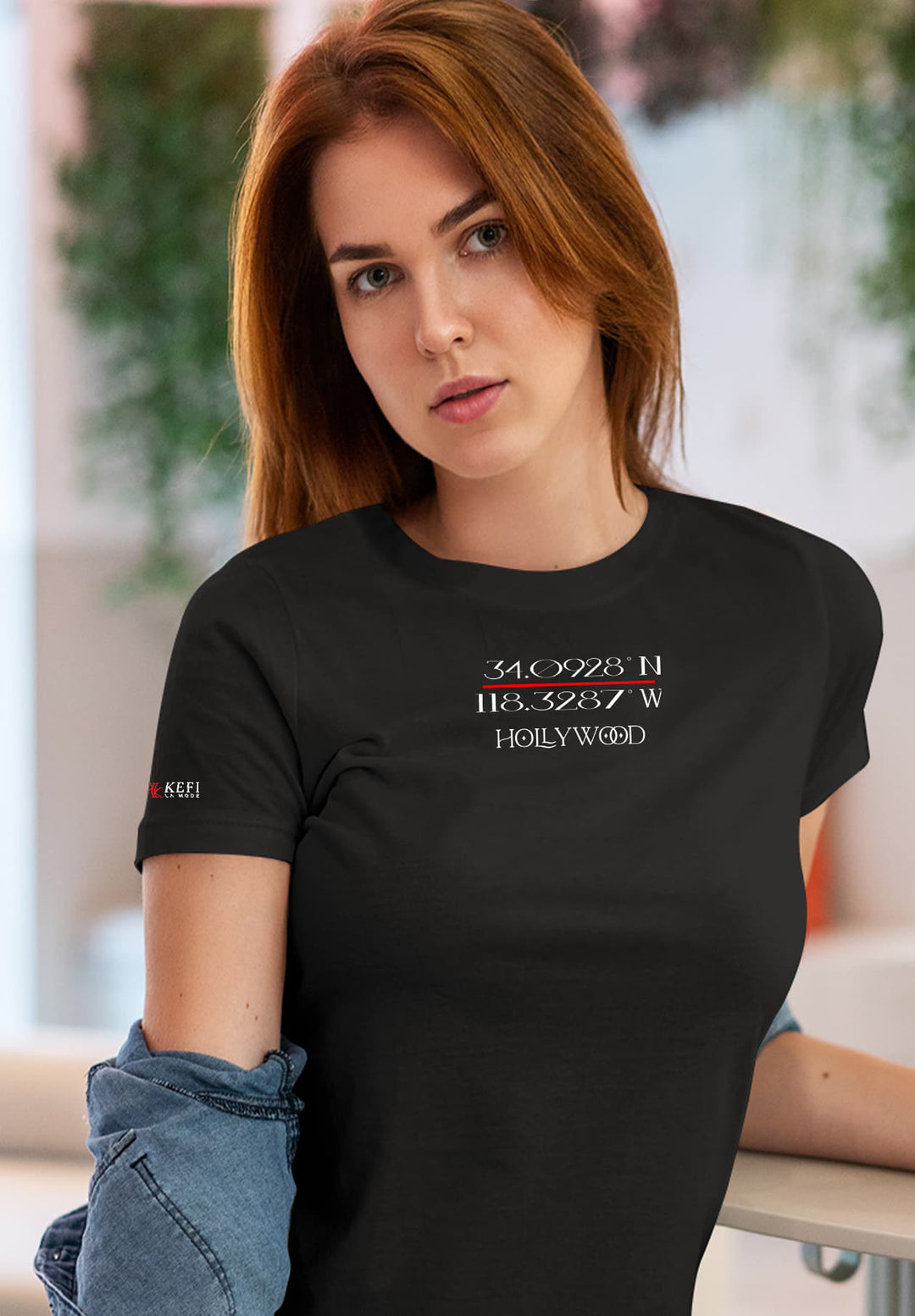 A woman sits elegantly in denim pants and a black T-shirt, radiating a carefree mix of fashion and ease.