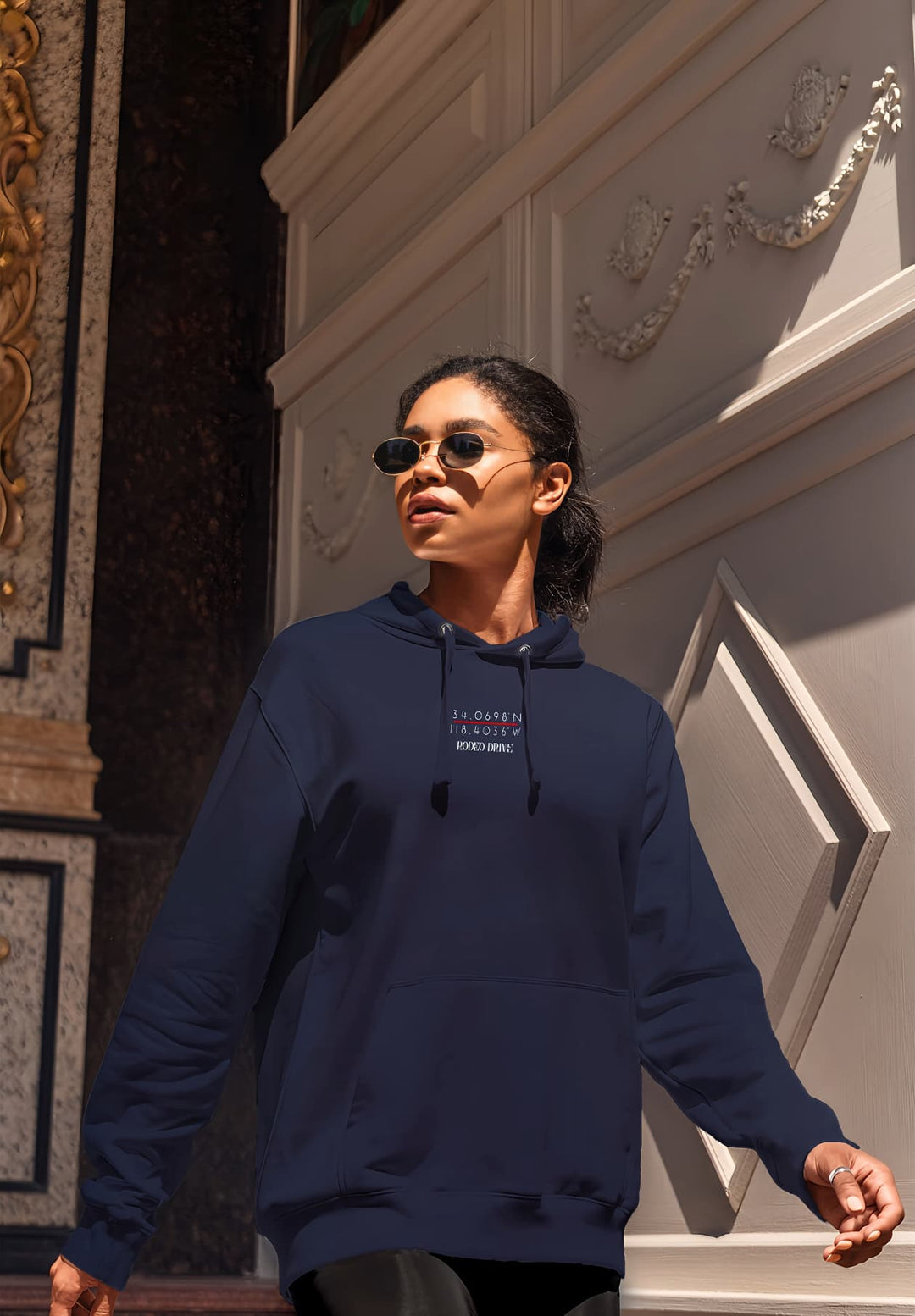 A young woman's fashion moment unfolds by an elegant building in a striking blue hoodie.