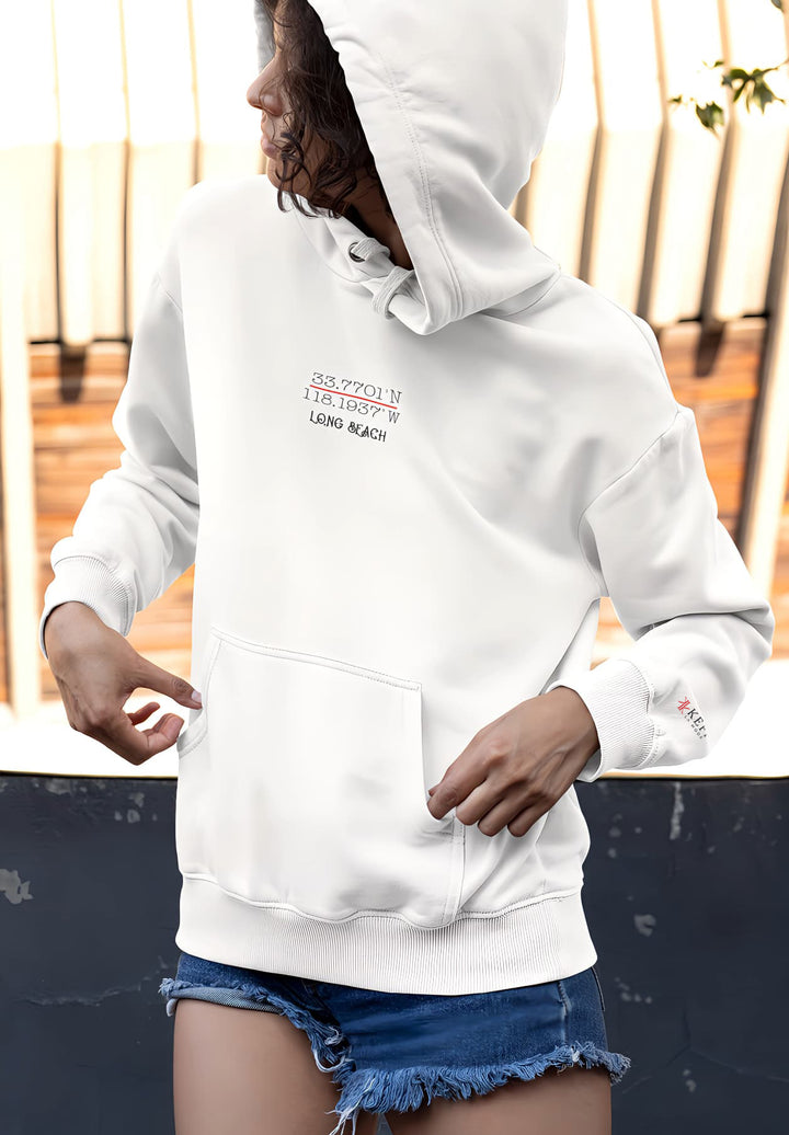 The woman in the white hoodie and shorts creates a scene that captures the essence of coastal relaxation and effortless style.